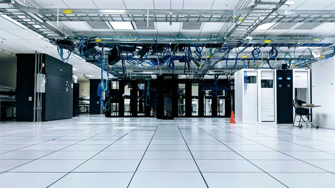 Data center server hall with overhead cable trays and cold-aisle server racks
